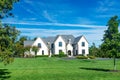 Large modern single-family luxury home with a large mowed lawn and beautiful landscaping. Sunny day and blue sky Royalty Free Stock Photo
