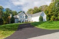 Large modern stone house on a hill with a large green lawn and bushes. Country two-story house. Blue sky on a summer day