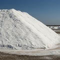 Large mound of salt is piled in a salt flat under a clear blue sky. The ground appears Royalty Free Stock Photo