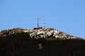 Large mountain top covered with dense forest and rock formations with building and multiple cell phone and TV towers