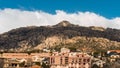 a large mountainside with buildings surrounding it and a bird flying high above the mountain Royalty Free Stock Photo