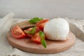 Large mozzarella with slices of tomatoes and basil on a wooden cutting board. Rustic style Royalty Free Stock Photo