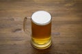 A large mug of light tasty cold beer on a wooden table, close-up,
