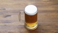 A large mug of light tasty cold beer on a wooden table, close-up,