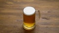 A large mug of light tasty cold beer on a wooden table, close-up,