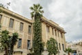 Large Neoclassic Building Facade in Downtown Helarclion, with a High Palm Tree on a Cloudy Day. Typical Street and Road with Cars Royalty Free Stock Photo