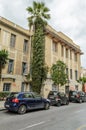 Large Neoclassic Building Facade in Downtown Helarclion, with a High Palm Tree on a Cloudy Day. Typical Street and Road with Cars Royalty Free Stock Photo