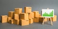 A large number of cardboard boxes and sign with green positive trend chart. rate growth of production of goods and products Royalty Free Stock Photo