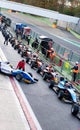 Large number of formula racing car aligned in circuit pit lane