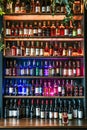 Large number of wine bottles displayed on shelves with few different colored lights illuminating them. Generative AI Royalty Free Stock Photo