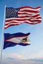 Large official Flag of US with smaller flag of American Samoa state, Usa at cloudy sky background. United states of America