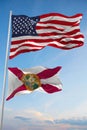 Large official Flag of US with smaller flag of Florida state, Usa at cloudy sky background. United states of America patriotic