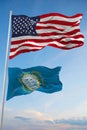 Large official Flag of US with smaller flag of South Dakota state, Usa at cloudy sky background. United states of America