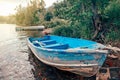 Large old blue boat and two paddles on shore beach. Beautiful landscape sunset view at Canadian Ontario Beech lake in Muskoka area