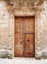 Large old brown wooden door covered with rusted iron studs keyhole and handle set in an ornate carved stone frame with surrounding Royalty Free Stock Photo