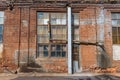 A large old dilapidated house made of colorful bricks with large dilapidated windows and a wooden door. Old dirty abandoned Royalty Free Stock Photo