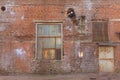 A large old dilapidated red brick house with a rusty window and a metal door. Old dirty abandoned factory building Royalty Free Stock Photo