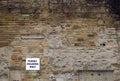 Large old outdoor brown stone wall with a parking sign that reads permit holders only