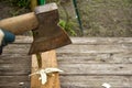 A large old rusty axe cut a thin branch of wood on a wooden table. Place for inscription