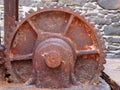 Large old rusty cogwheel on obsolete heavy machinery against a stone wall Royalty Free Stock Photo