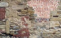 large old wall made of mixed bricks and stone with many jumbled patched and uneven repairs