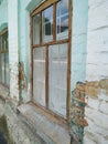 Large old window in a wooden frame. Brick house with shabby pale green paint. Royalty Free Stock Photo