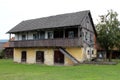 Large old wooden family house with raised front porch and dilapidated boards next to concrete well with rusted water pump