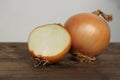 Large onion whole and cut on a wooden table, concept of vegetables for health against colds, horizontal, closeup, copy space