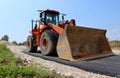 Large orange bulldozer on a half paved road at the construction site