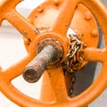 Large orange iron round valve on a long rusty bolt pressure adjustment flow industrial grunge style background
