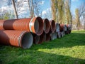 Large orange sewer pipes lie on the ground in two rows