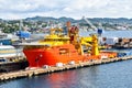 A large orange and yellow colored Offshore Construction Vessel OCV is in a dry dock of a shipyard and is being repaired Royalty Free Stock Photo