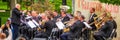 a large orchestra plays music in a city park on a summer day