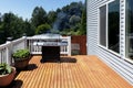 Large outdoor BBQ cooker with smoke coming out while on home wooden deck Royalty Free Stock Photo