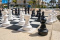 Large outdoor chess set at a resort poolside on a sunny day