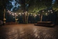 large outdoor dance floor surrounded by twinkling lights and towering trees