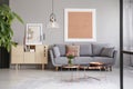 Large painting on a gray wall above an elegant sofa with cushions in a stylish living room with copper furniture