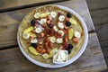 Large pancake with fresh summer fruit and whipped cream on a wooden table. Top view