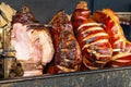 Large part of meat cooked on a rotate grill over open fire. Grilled prepared outdoors. Smoked grilled Old Prague ham