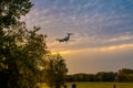 A large passenger plane goes on landing at sunset. shooting in the park against the background of autumn trees Royalty Free Stock Photo