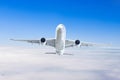 Large passenger white airplane flies in a blue sky with a bright sun.