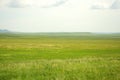 A large pasture in a steppe bathed in sunlight surrounded by high hills Royalty Free Stock Photo