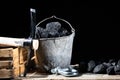 Large pickaxe with wooden handle on black background with lumps of black coal