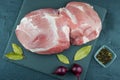 a large piece of fresh blue meat on a slate stone and a black background with laurel leaf, onion and pepper. top view.