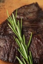A large piece of grilled meat with a rosemary branch on a wooden board. Close-up Royalty Free Stock Photo