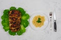 A large piece of pork cooked in the oven, baked in the oven, on green lettuce leaves. With pasta on a plate with a fork Royalty Free Stock Photo
