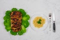 A large piece of pork cooked in the oven, baked in the oven, on green lettuce leaves. With pasta on a plate with a fork Royalty Free Stock Photo
