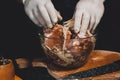 A large piece of pork is cut into pieces, marinated by the chef with spices, and the chef rubs the potatoes on a grater to the Royalty Free Stock Photo