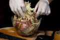 A large piece of pork is cut into pieces, marinated by the chef with spices, and the chef rubs the potatoes on a grater to the Royalty Free Stock Photo