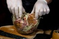 A large piece of pork is cut into pieces, marinated by the chef with spices, and the chef rubs the potatoes on a grater to the Royalty Free Stock Photo